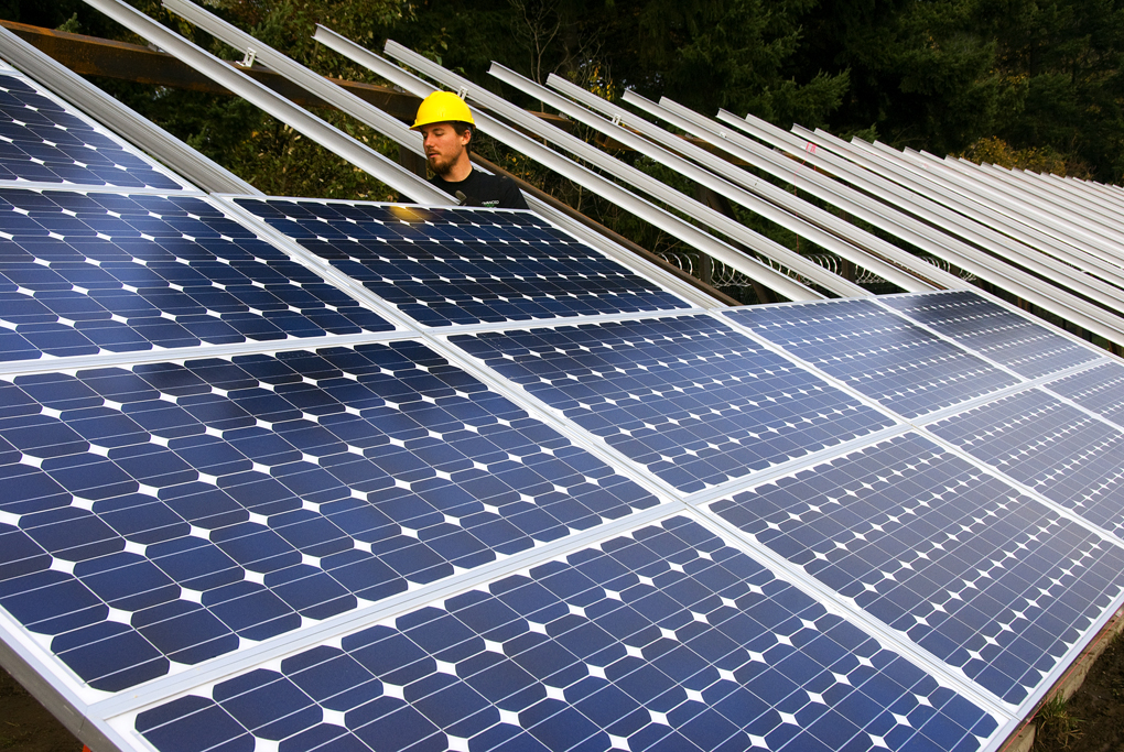 A person in a hard hat assembles solar panels.